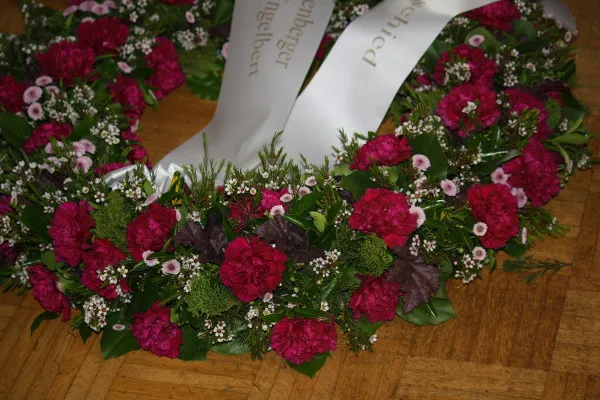 Trauerkranz aus pinkfarbenen Nelken und Wachsblumen mit Schleife