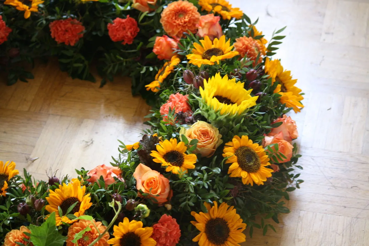 Herbstlicher Kranz aus Sonnenblumen, orangen Rosen und Dahlien